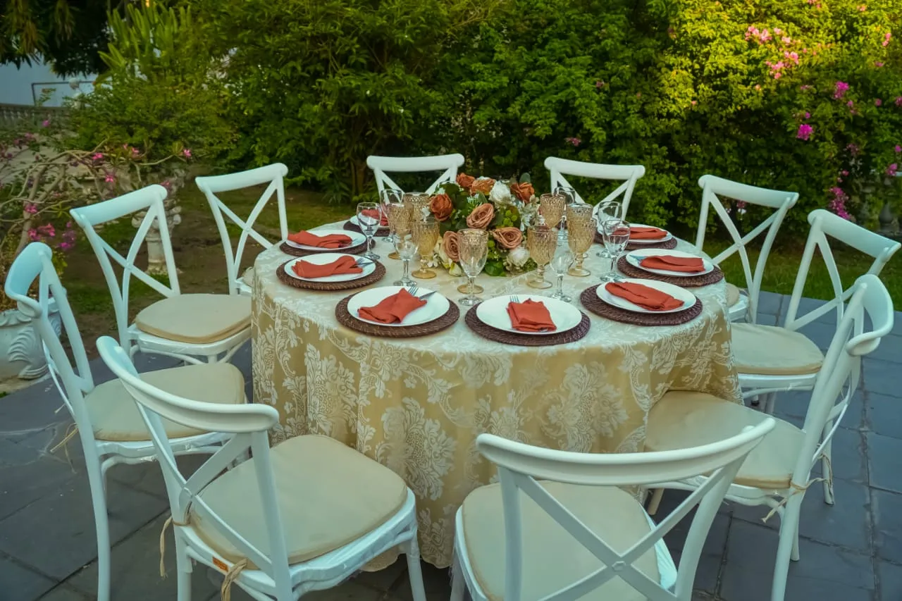 Mesa posta com cadeiras brancas no jardim
