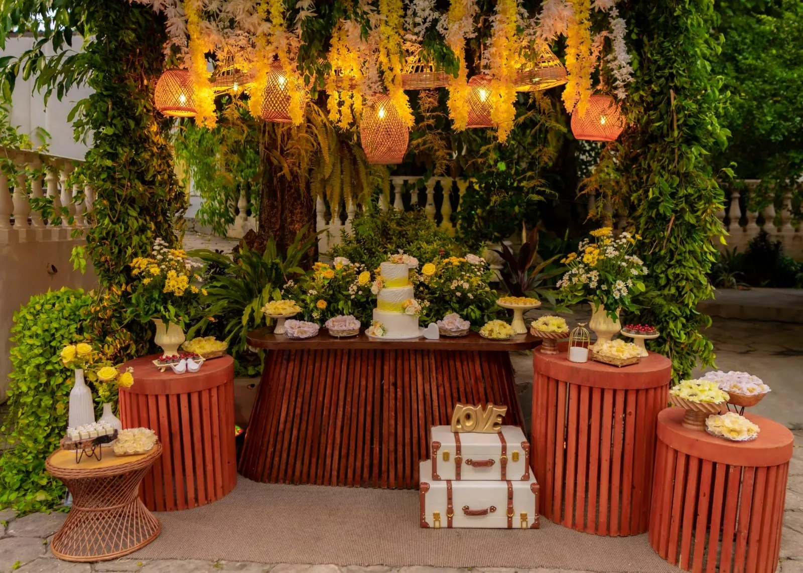 Mesa de doces rústica com flores amarelas e luminárias de palha